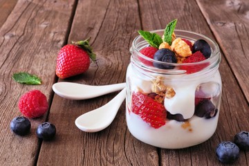 Strawberry, blueberry and raspberry parfait in a mason jar. still life on rustic wood background.