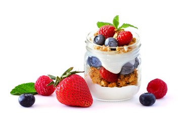 Healthy berry fruit parfait in a mason jar with scattered fruit isolated on a white background