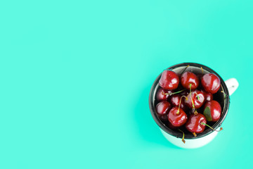 ripe cherries delicious in iron mug on blue background, summer, vitamins, healthy food
