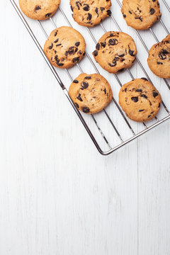 American cookies with chocolate chips on the grate fof oven on white wooden background. Top view with place for text.