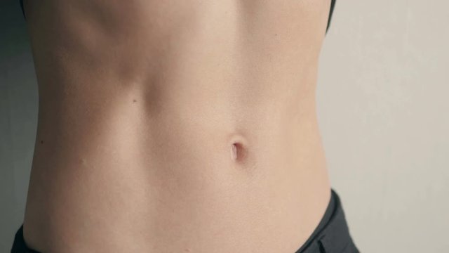 Close-up of the abdominal muscles young athlete on gray background