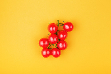 Bunch of fresh cherry romatoes on yellow background. Top view, minimal styled composition.