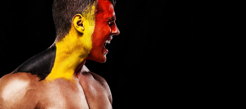 Soccer or football fan with bodyart on face with agression - flag of Belgium.