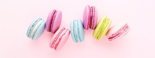Colorful macarons cookies on pink background. Top view, minimal, banner for site.