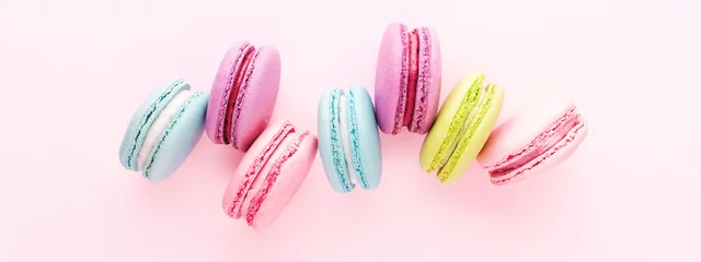 Keuken spatwand met foto Colorful macarons cookies on pink background. Top view, minimal, banner for site. © Olga Zarytska