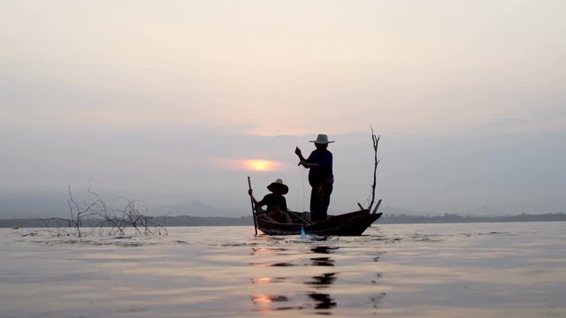 Scenic of fisherman family hunting fish in river by throwing fishing net background with sunrise
