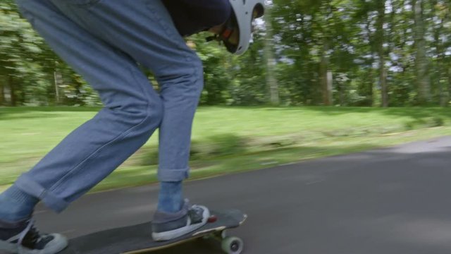 Young man in helmet touching the ground when skateboarding and enjoying warm summer day in park