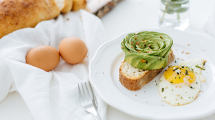 Breakfast setting featuring avocado rose on toast, and sunny side up egg.