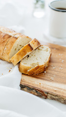 Loaf of bread sliced on wood cutting board and white linen.