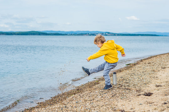 Young boy throwing stones in sea water