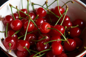 Obraz na płótnie Canvas Bowl of fresh red cherries on dark background. Raw Red Organic Cherries food, close-up, outdoors 