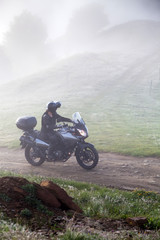 man riding a motorbike on foggy road in early morning