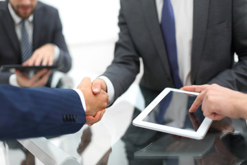 Men shaking hands with smile at office with their coworkers.