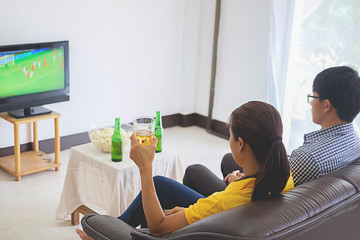 People watch soccer. Asian football supporters watching soccer on television at home with happy emotion.