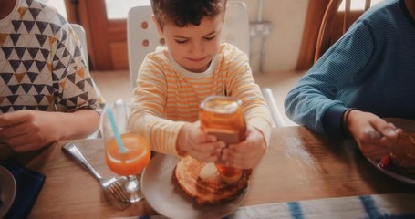 Boy eating pancakes for breakfast with siblings in the morning - Powered by Adobe