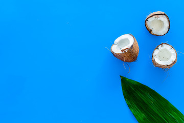 Tropical composition with coconut. Whole coconuts and coconut cut in half near pulm leaves on blue...
