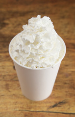 Drink with Whipped Cream on Top in a Disposable Cup on a Wooden Table