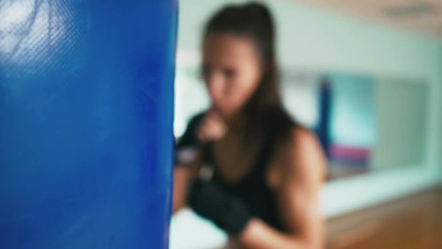 Beautiful Mixed Race Kickboxing woman training punching bag in fitness studio fierce strength fit body kickboxer series