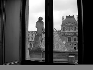 Inside the Louvre Museum, looking out a glass window at the top of the entrance pyramid in Paris, France.