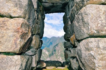 Peeking through a rock window at the Andes Mountains on top of Machu Picchu, Peru.