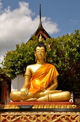 Obraz premium Golden buddha statue in saffron robes sitting in the lotus position