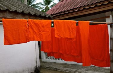 Saffron robes of buddhist monks hanging to dry on a bamboo poles
