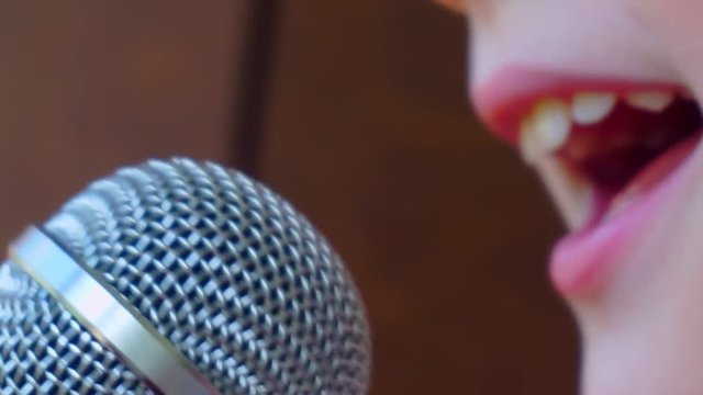 child's mouth sings into the microphone.close-up