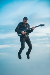 Naklejka premium Man playing guitar at sky background. Freedom and creativity concept