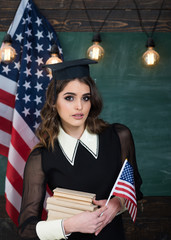 Group four happy people having waving American flag. American flag blackboard. Education university and school system in The United States of America. Concept with US flag and graduation hat symbol - obrazy, fototapety, plakaty