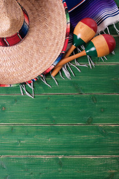 Mexico cinco de mayo fiesta carnival traditional green wood background border mexican sombrero maracas and serape rug or blanket photo vertical