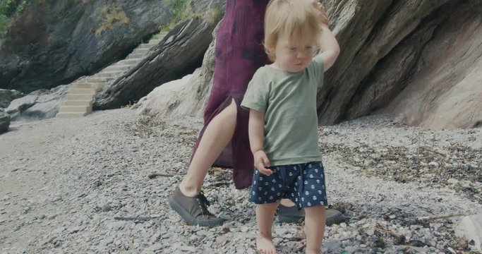 Young mother walking with her toddler boy on the beach