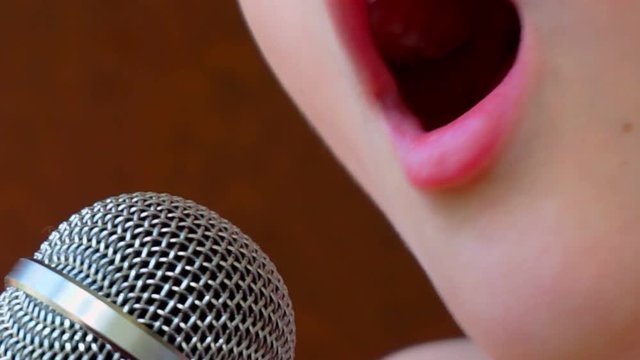 child's mouth sings into the microphone.close-up