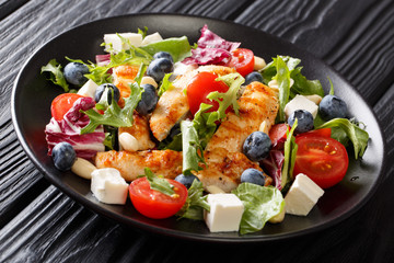 Dietary snack salad with blueberries, feta, chicken, nuts, tomatoes and lettuce close-up. horizontal