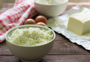 fresh rustic cottage cheese and eggs on wooden background, baking ingredients