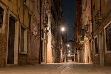 Fototapeta na wymiar Night view of a small street in Venice, Italy. Architecture and sights of Venice. Nightlife in Venice. Venetian postcard with a night view