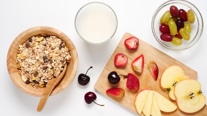 Top view of Oatmeal flakes, milk, and fresh fruits on white background.