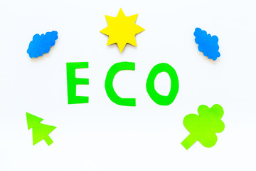Eco icon cutout near environment symbols as sun, trees, clouds on white background top view