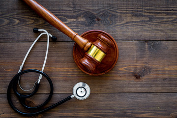 Medical law, health law concept. Gavel and stethoscope on dark wooden backgound top view copy space