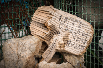 Small wooden sign saying Let's clean this beach