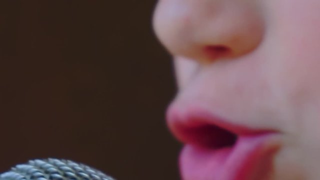 mouth of a boy singing into a close-up microphone