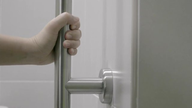 Woman holding on handrail in toilet.