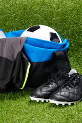 soccer ball, in a sports bag and a T-shirt, a water bottle, black boots, on a grass background