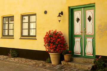 Fototapeta na wymiar View of a yellow - painted house and a front door. Small Danish town with narrow cobbled street.