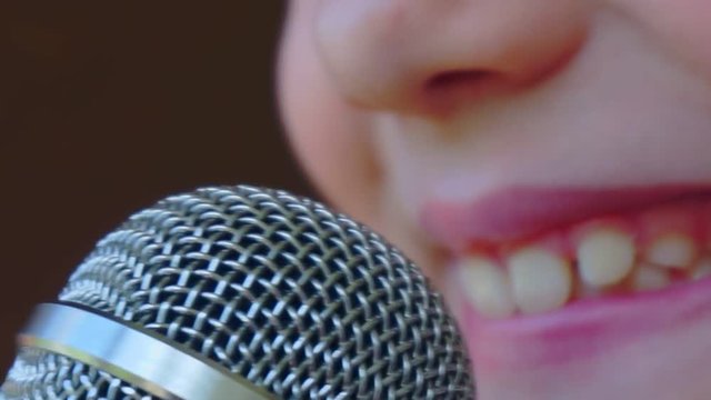 mouth of a child singing into a close-up microphone.