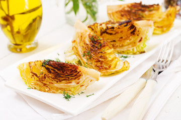 Vegan grilled cabbage steaks on white wooden background. Healthy food.