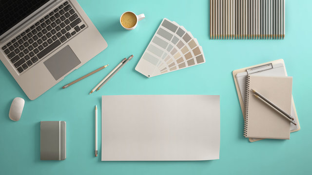 Stylish minimal office table desk. Workspace with laptop, notebook, pencils, coffee cup and sample color palette on pastel turquoise background. Flat lay, top view, blank paper mockup template