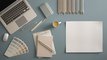 Stylish minimal office table desk. Workspace with laptop, notebook, pencils, coffee cup and sample color palette on pastel blue background. Flat lay, top view, blank paper mockup template