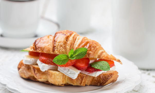 Croissant with strawberries, brie cheese or Camambert and mint. Delicious gourmet Breakfast