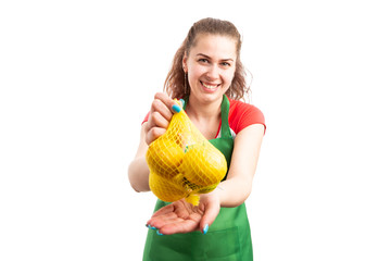 Woman supermarket or retail worker offering bag of lemons.