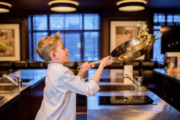 Little boy dressed like a cook has fun on the kitchen